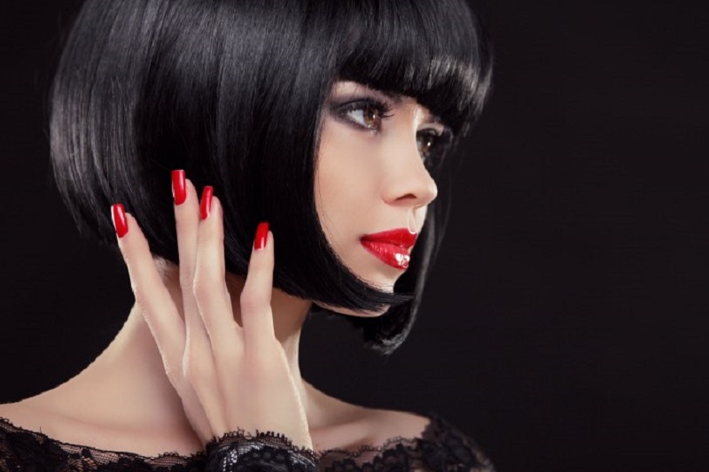 Bob coupe courte noire. Ongles manucurés et lèvres rouges. La mode